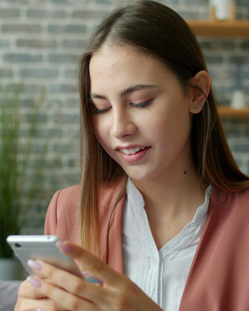 Mujer sonriendo mientras escribe en su celular